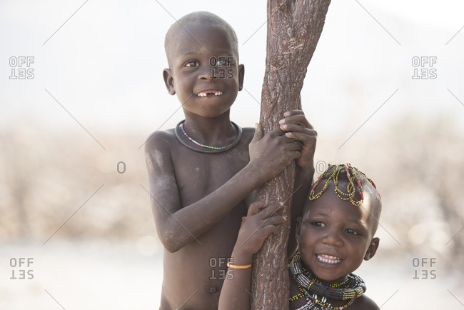 Happy siblings standing by tree