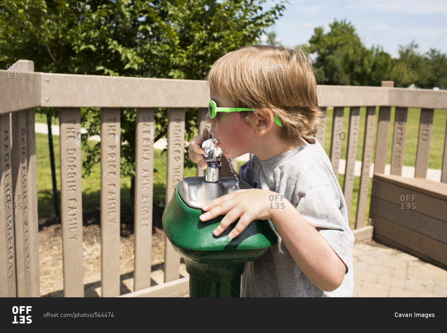 Boy drinking water from fountain at park