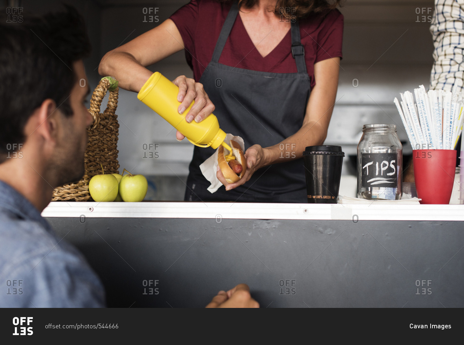 Midsection of female vendor serving hotdog for customer at food truck