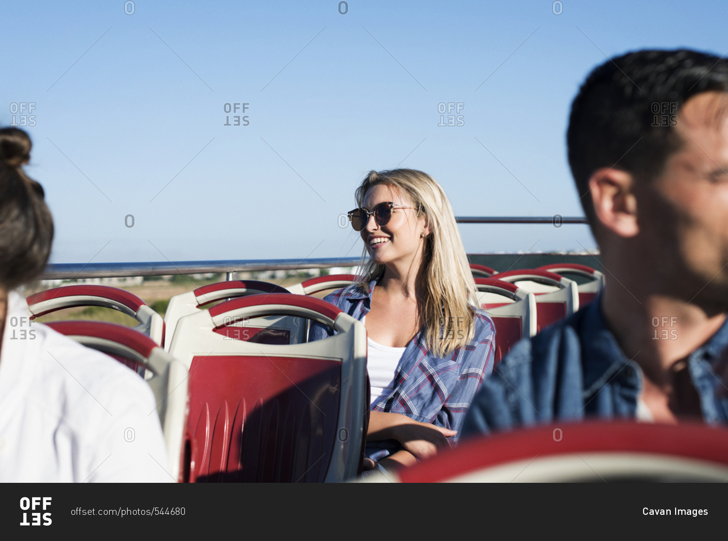 Tourists traveling in double-decker bus against clear blue sky