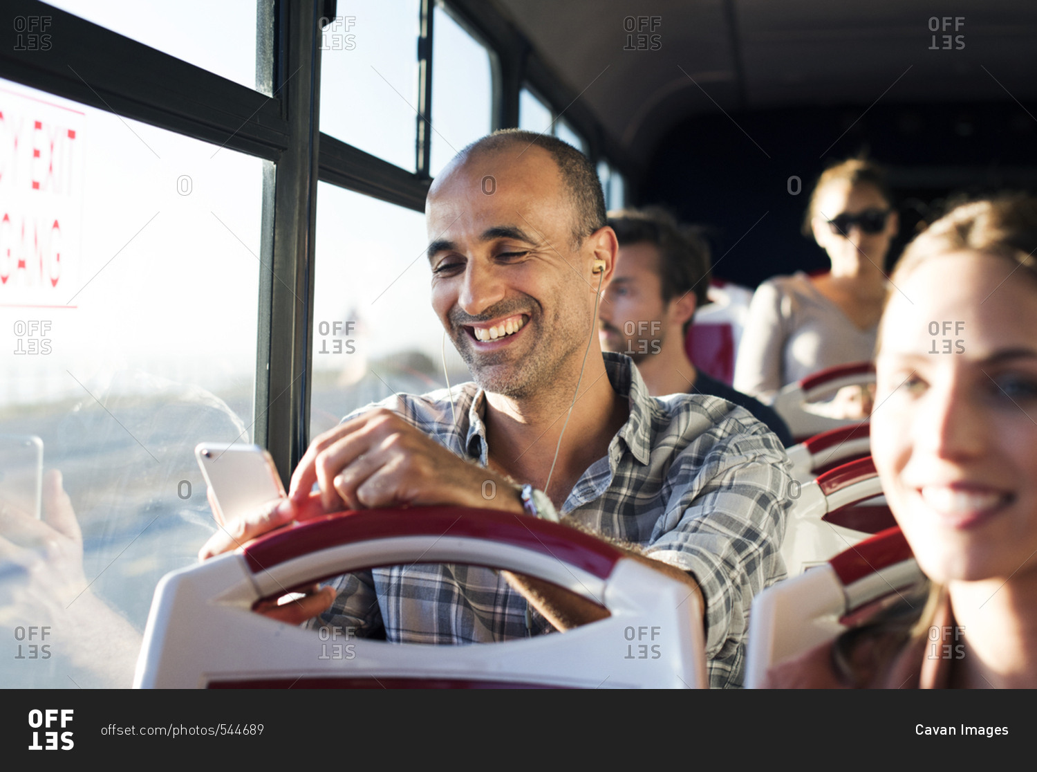 Happy man using mobile phone while traveling in tour bus