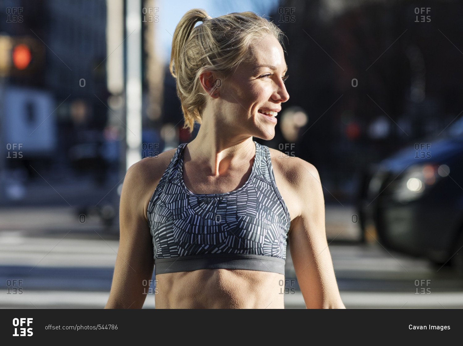Female athlete looking away while standing on street during sunny day