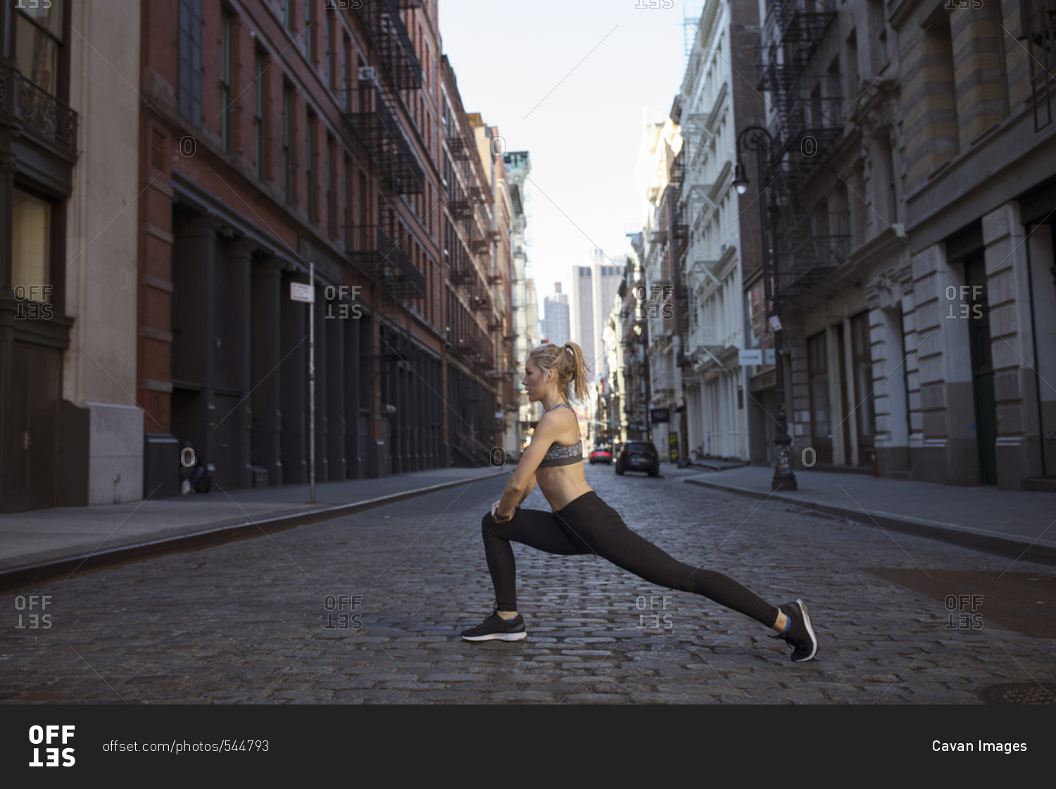 Side view of woman exercising on street in city