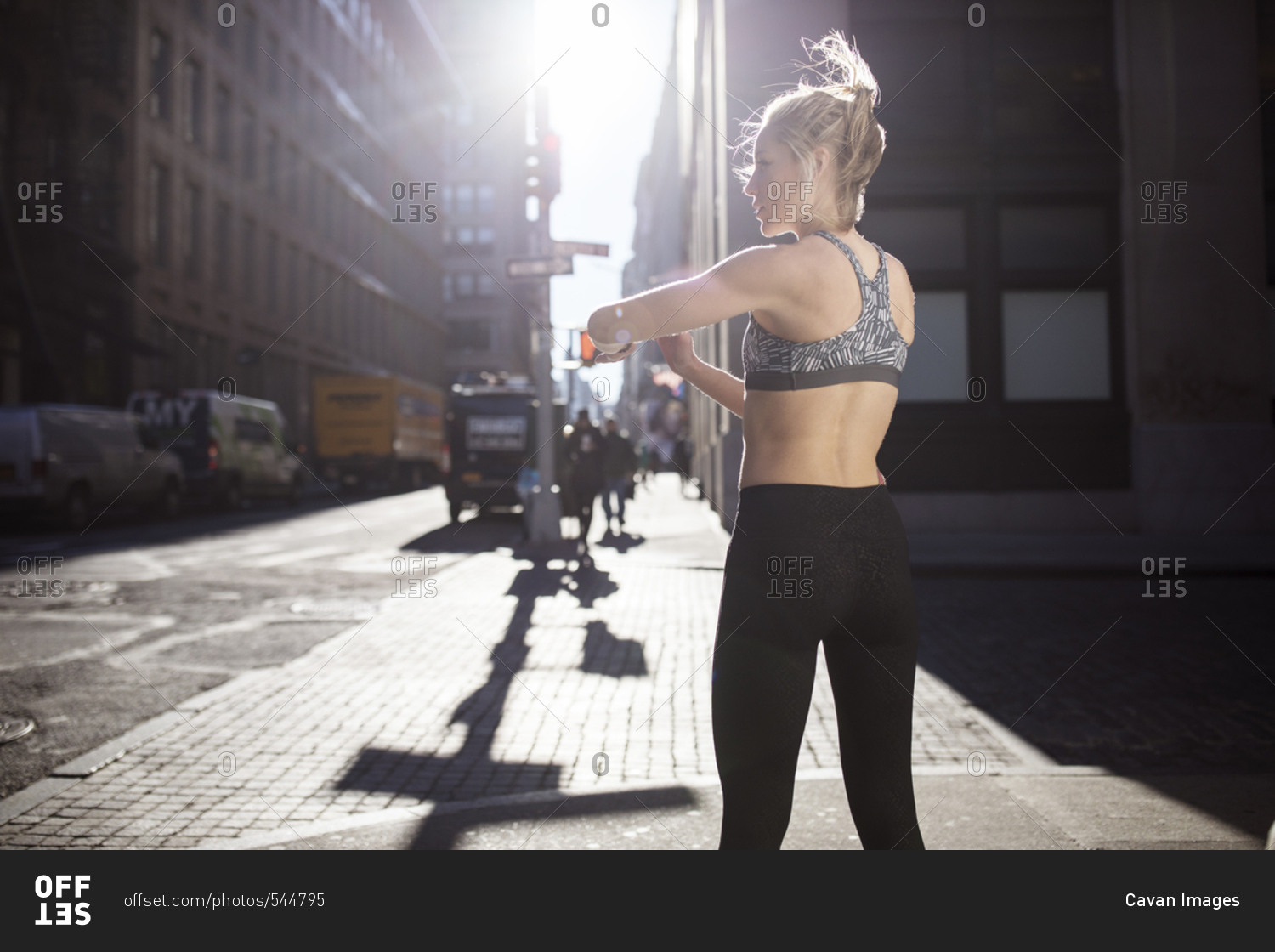 Rear view of female athlete standing on city street during sunny day