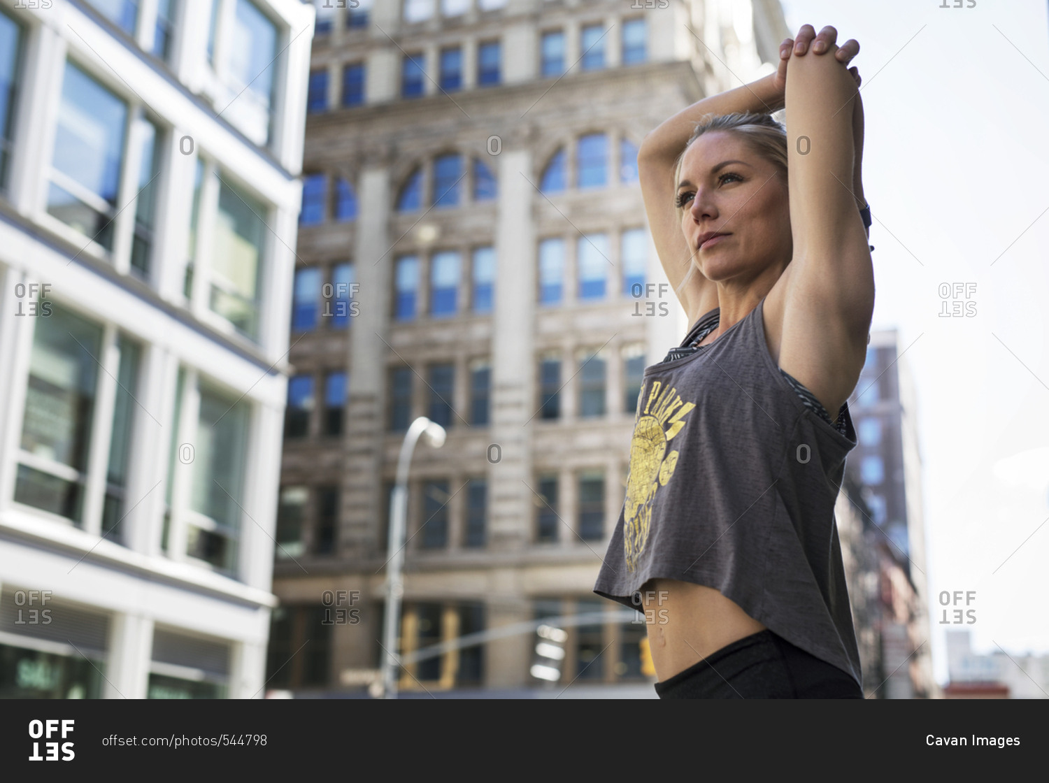 Low angle view of confident athlete stretching hands on city street
