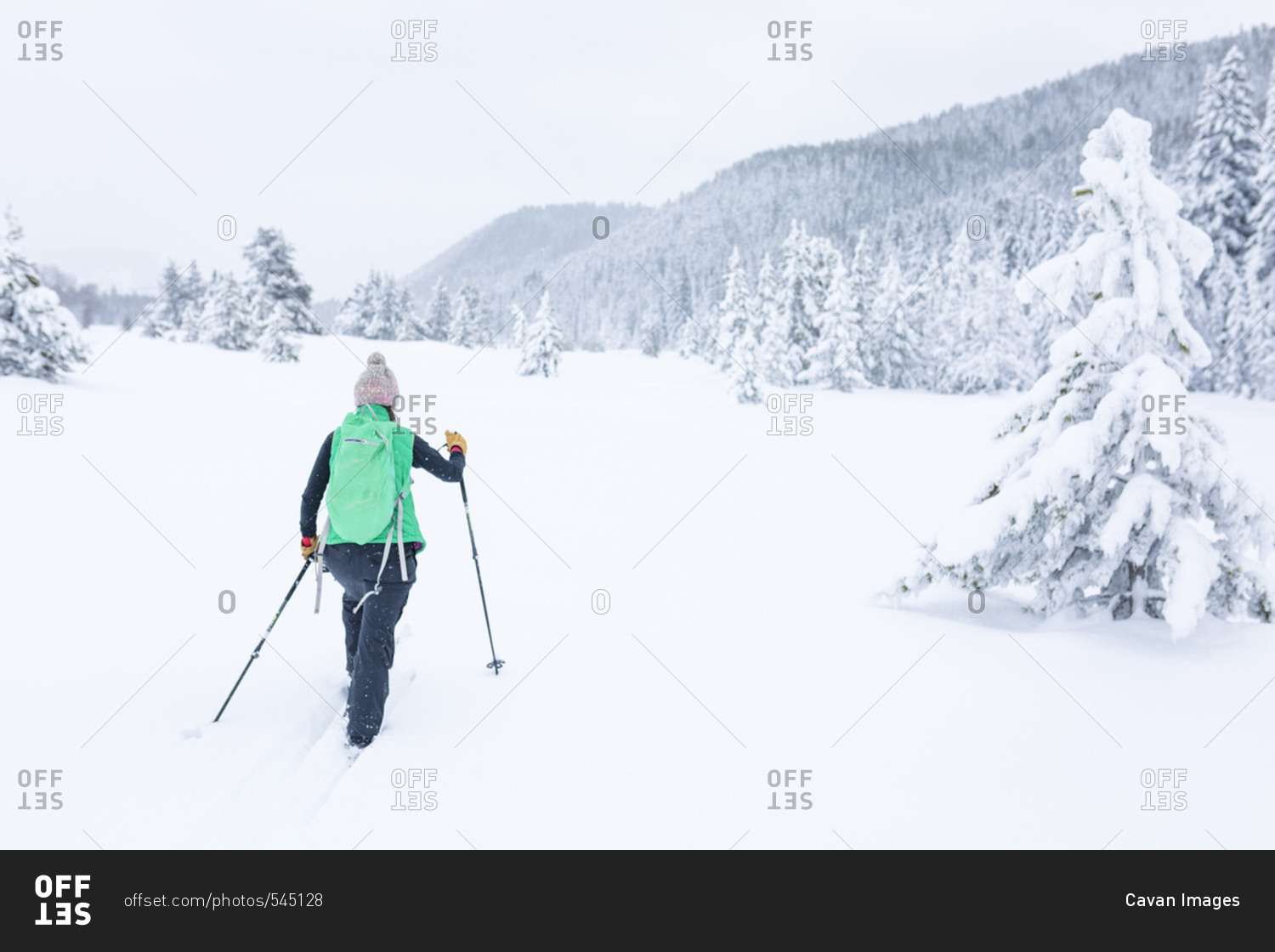 Rear view of female hiker hiking on snow covered field
