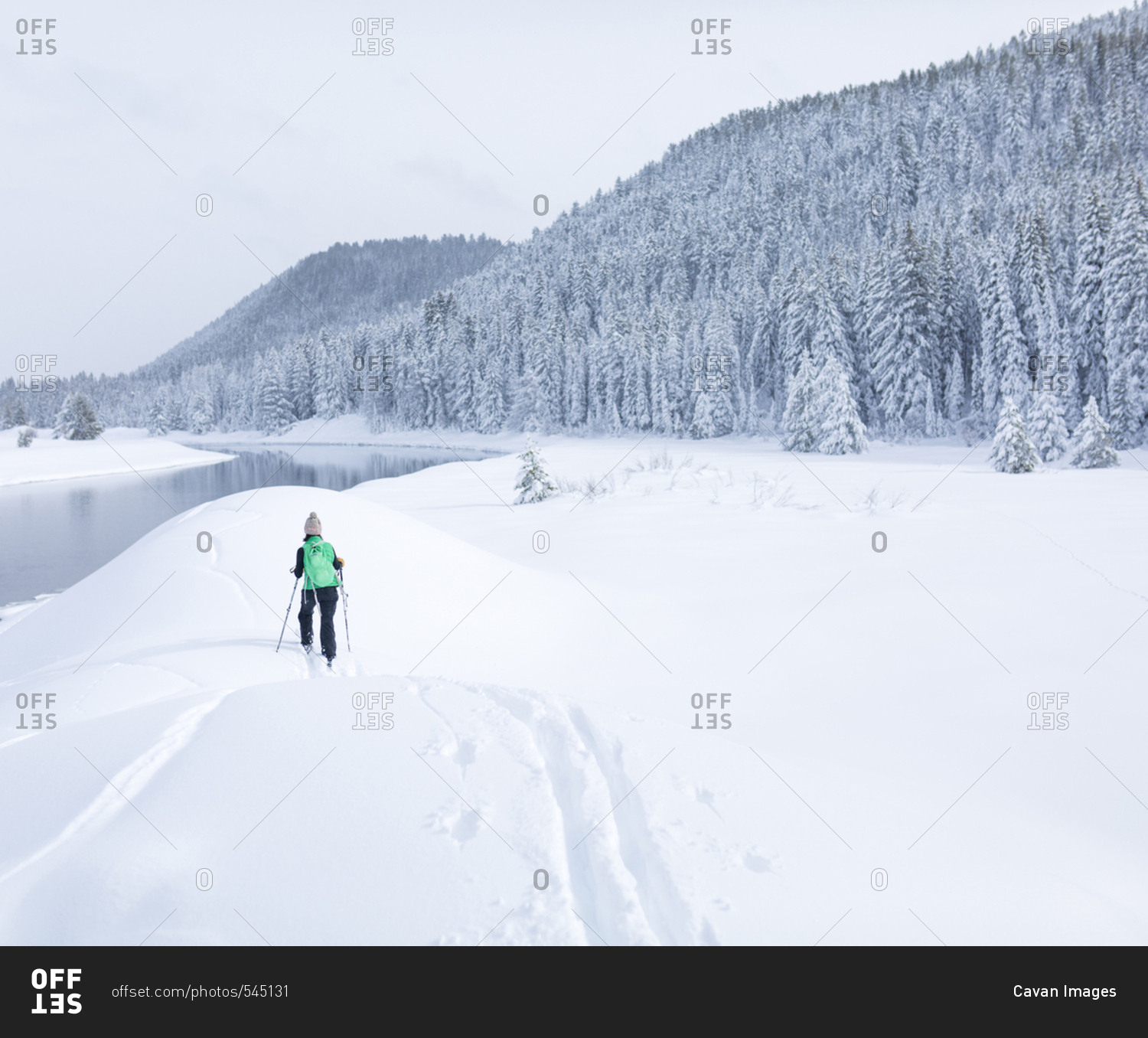 Rear view of female hiker hiking on snow covered field against sky