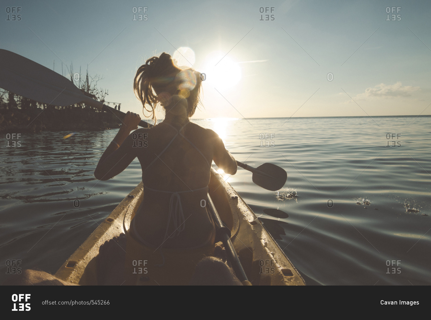 Rear view of woman rowing boat in sea against sky