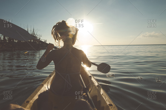 Rear view of woman rowing boat in sea against sky