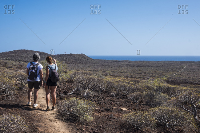 Two hikers looking at a distant lighthouse on an island