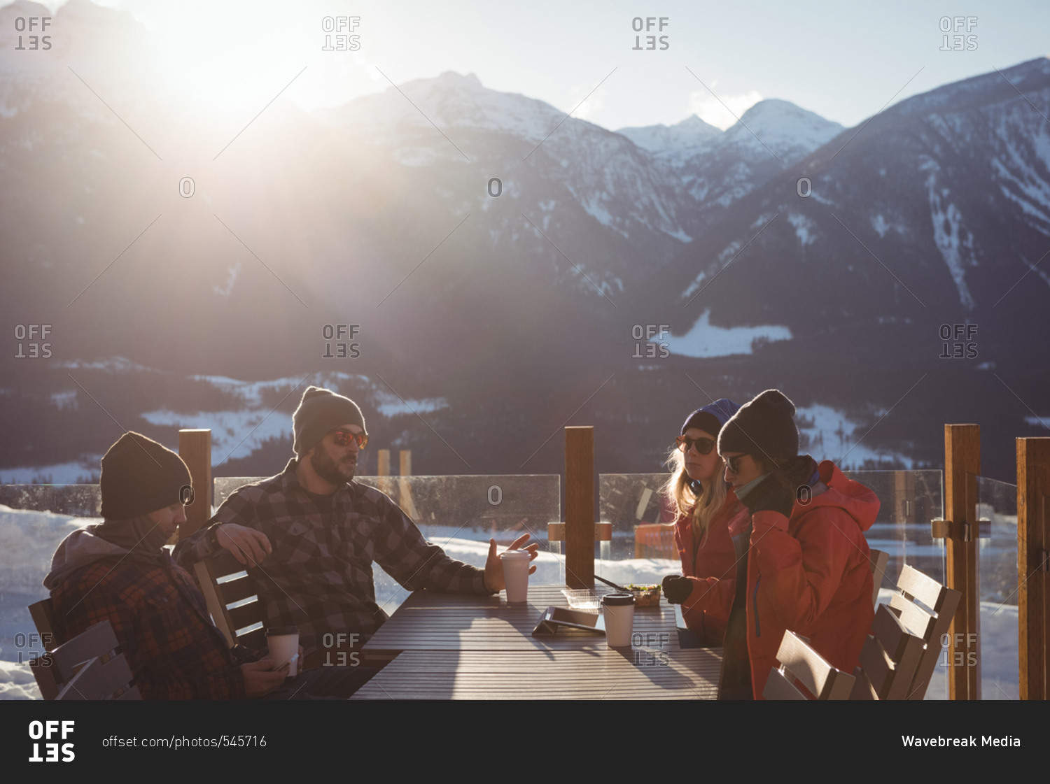 Skiers interacting with each other while having cup of coffee