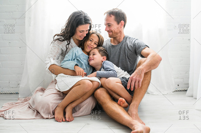 Family cuddling on floor in front of window
