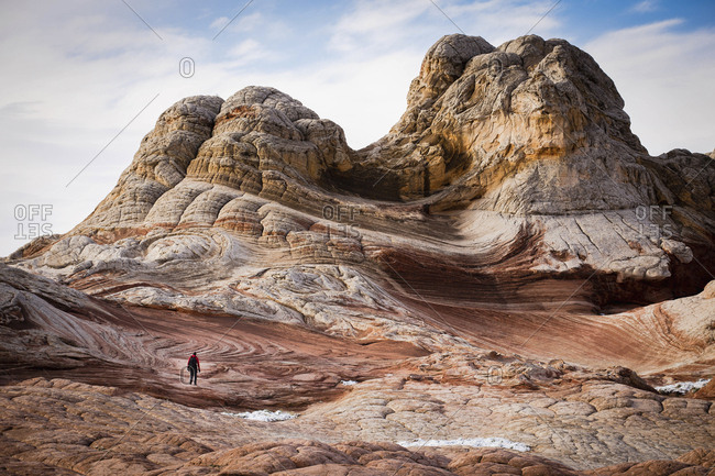 A person in a vast landscape, of buttes and geological formations, red sandstone layers of rock Arid and barren rocks