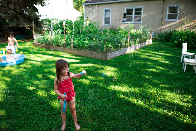 Young girl in backyard blowing bubbles