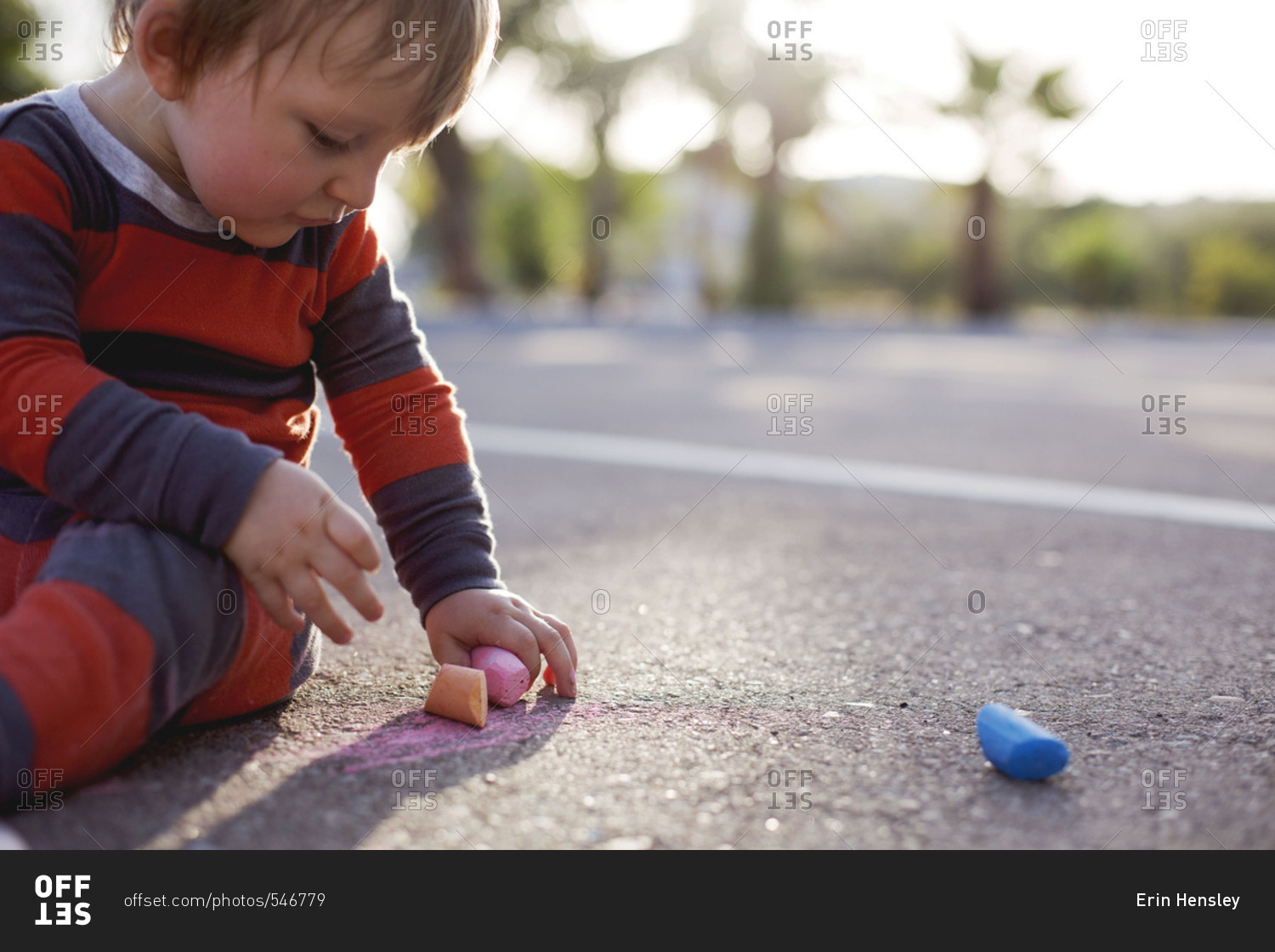 Close-up of baby drawing on pavement with chalk