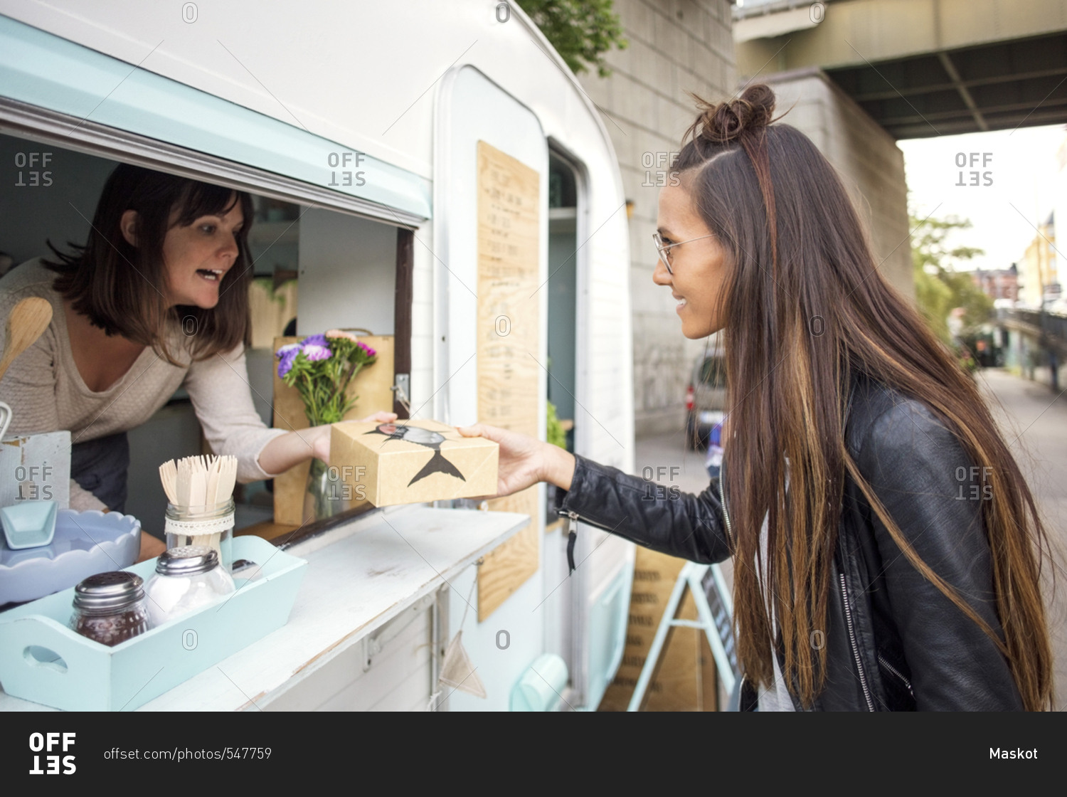 Side view of woman buying food from female owner at food truck