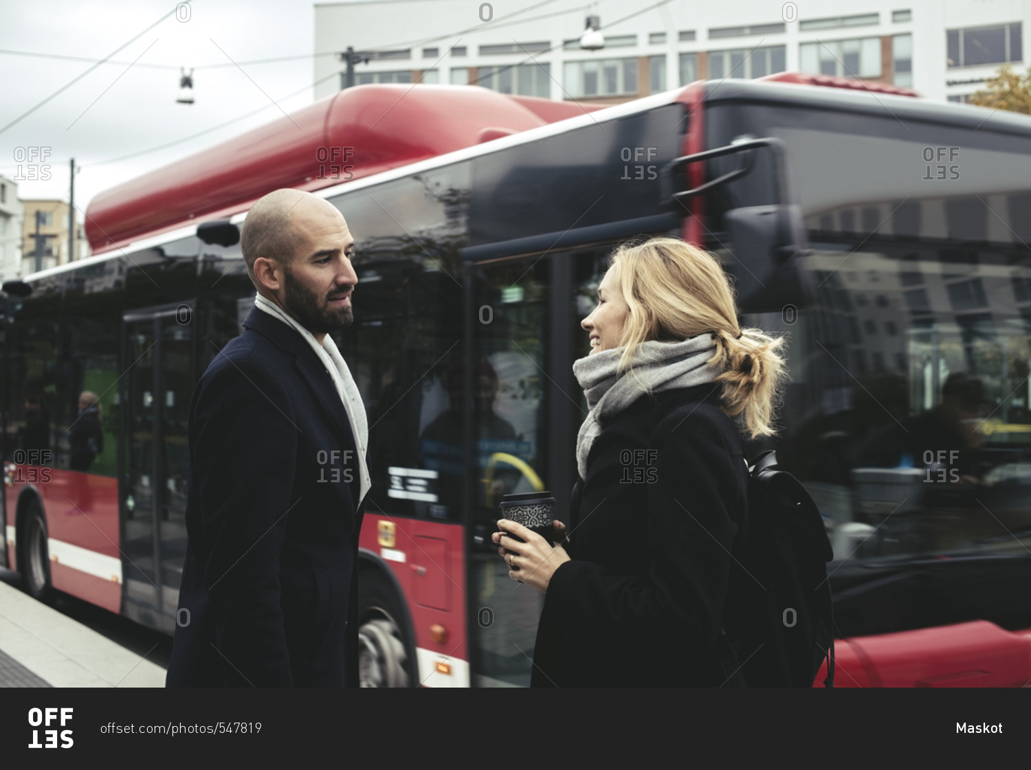 Business people talking on sidewalk by bus in city