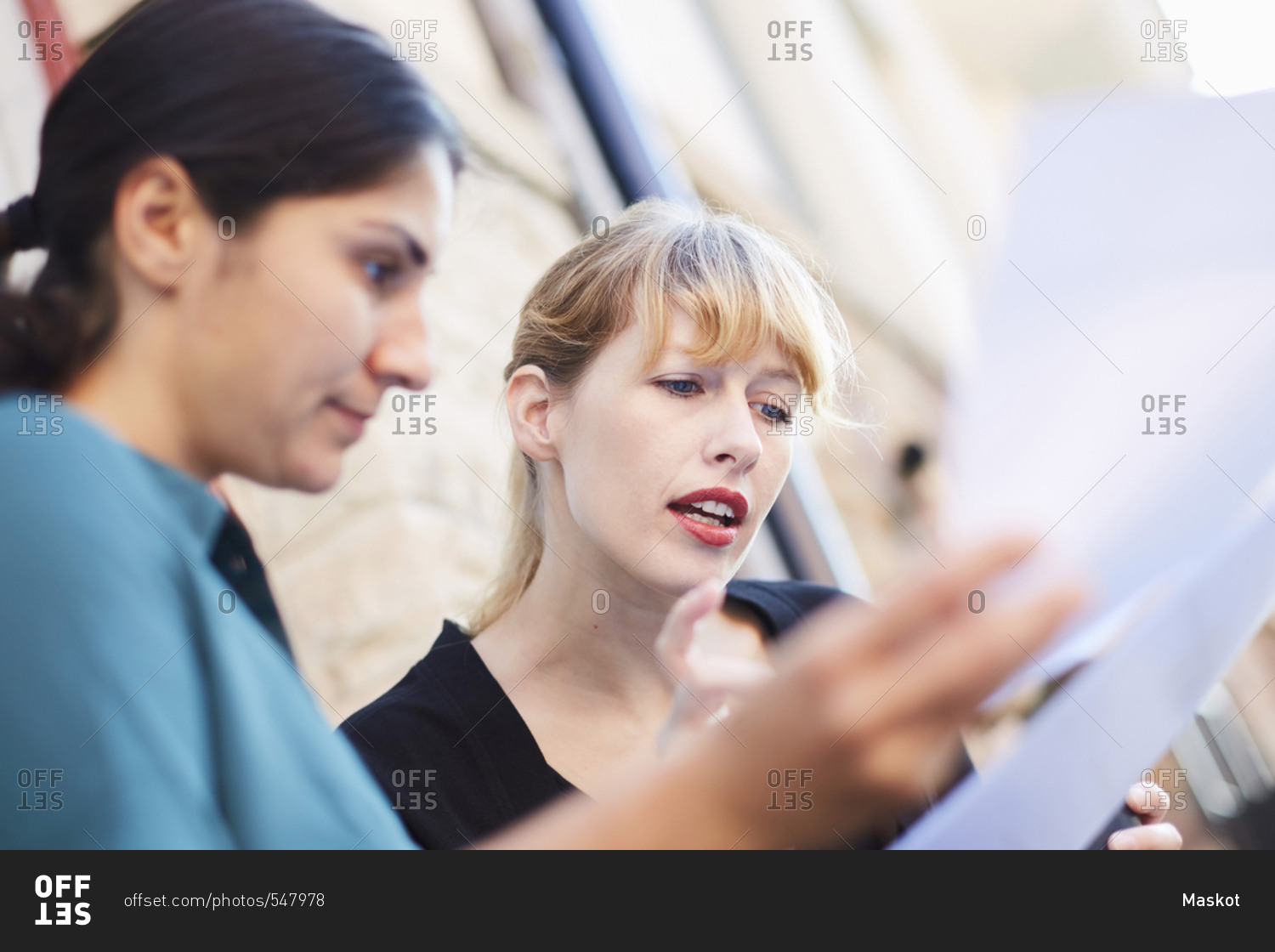Mid adult businesswomen discussing over documents outside office