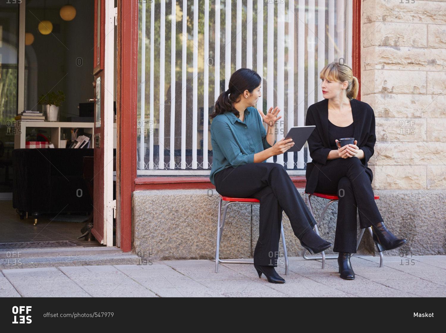 Full length of businesswoman discussing with female colleague outside office