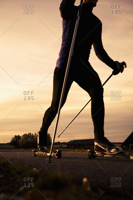 Low angle view of mature man roller skiing on road against sky during sunset
