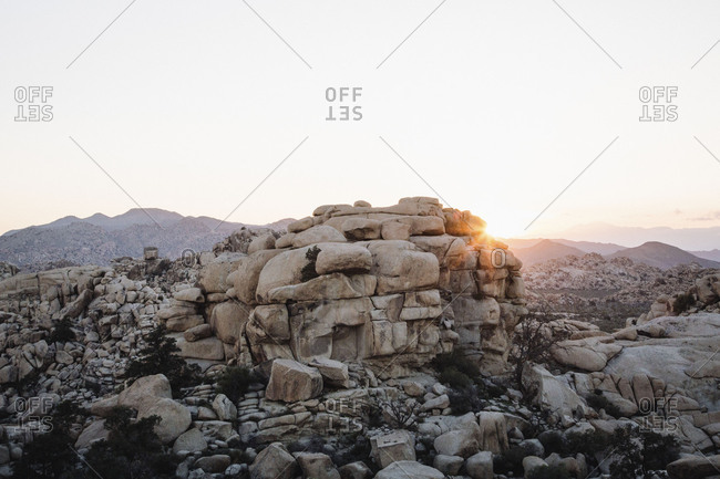 Sun setting over mountains and rock formations in the desert