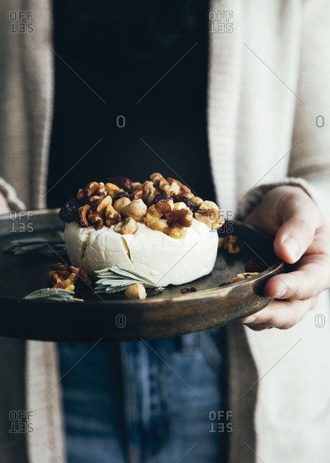 Woman holding fresh cheese with nuts