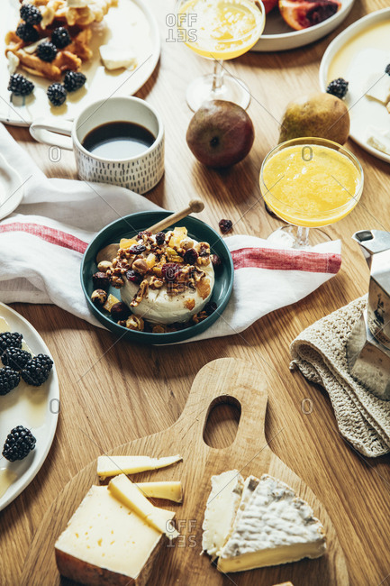 Decadent breakfast of waffles, pastries, fruit and cheese arranged on a wooden table