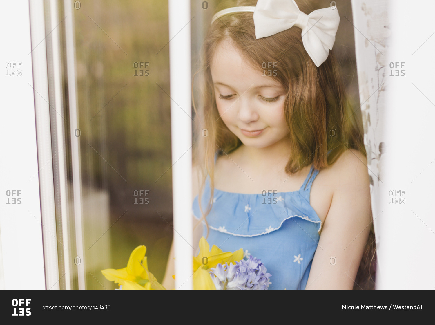 Portrait of smiling girl with cut flowers behind windowpane