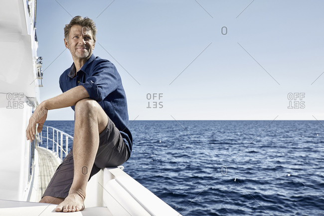 Smiling mature man on motor yacht looking at distance