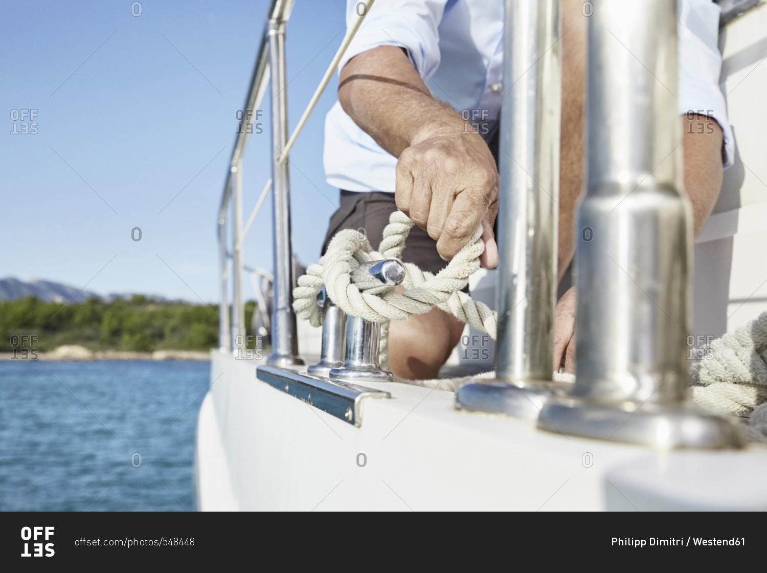 Mature man on motor yacht tying a knot- partial view