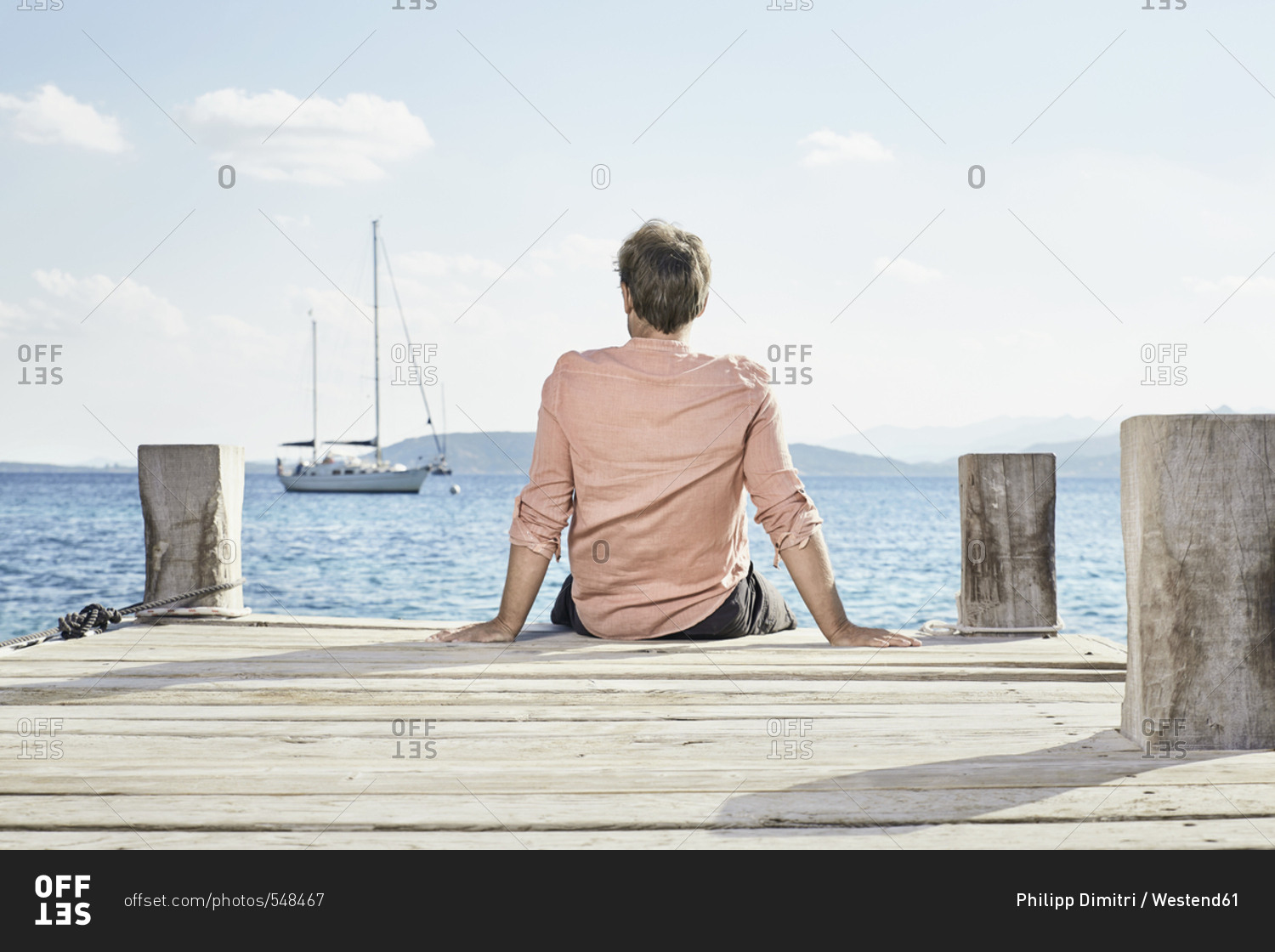 Back view of man sitting on jetty looking at distance
