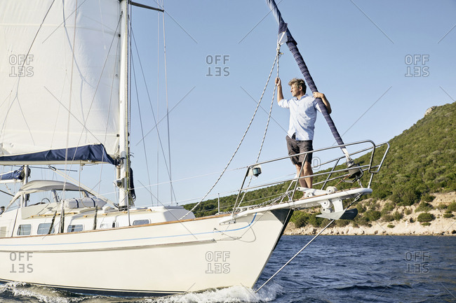 Man standing on bow of his sailing boat looking at distance