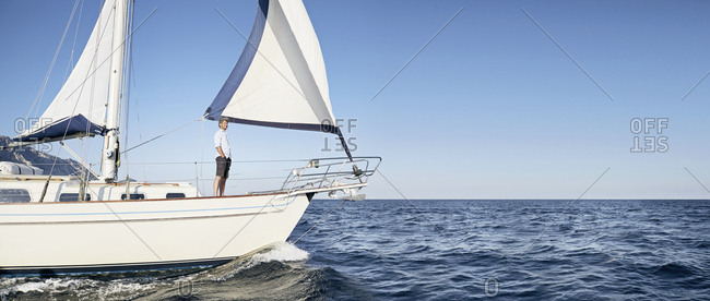 Mature man standing on his sailing boat looking at distance