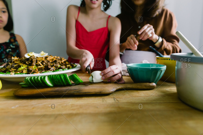 Woman teaching her granddaughters to prepare traditional Indonesian meal