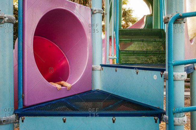 Child holding onto top of slide on a playground