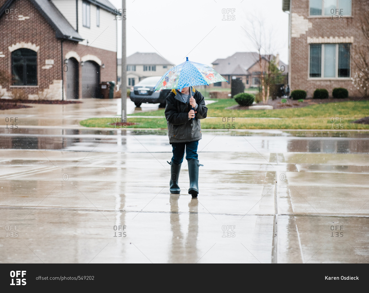 Young boy walking with umbrella in the rain