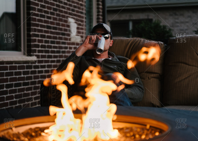 Man sitting by fire pit drinking a beer