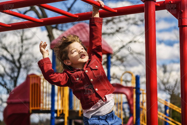 Young boy trying to do the monkey bars at a playground