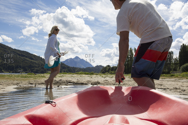Mature couple haul kayak out of mountain lake