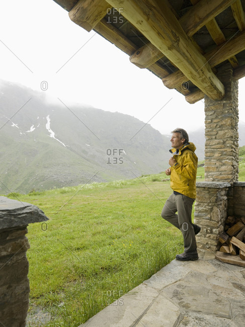 Hiker zips up raincoat leaving shelter in mountains