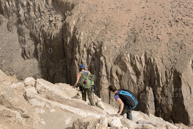 Two Female Climbers Begin A Steep Decent Into Owens River Gorge In Bishop, California, Usa