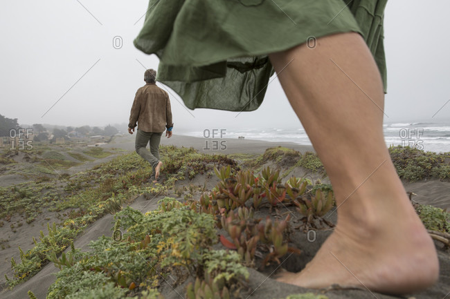 Detail of woman's foot and distant man, foggy coastline