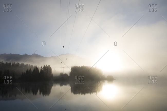 Powerlines leading into misty sunrise over mountains
