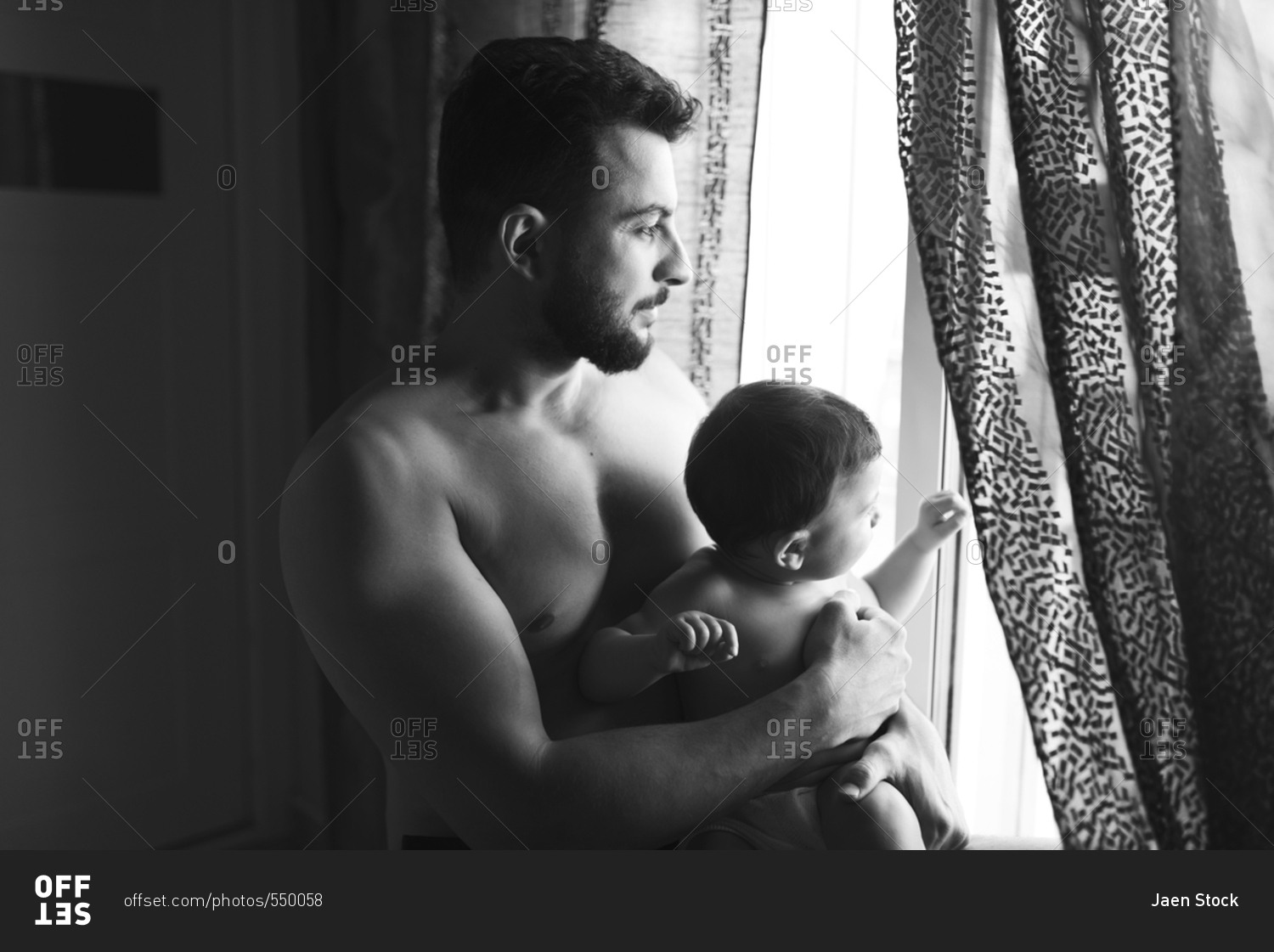 Father holding baby son in home bedroom