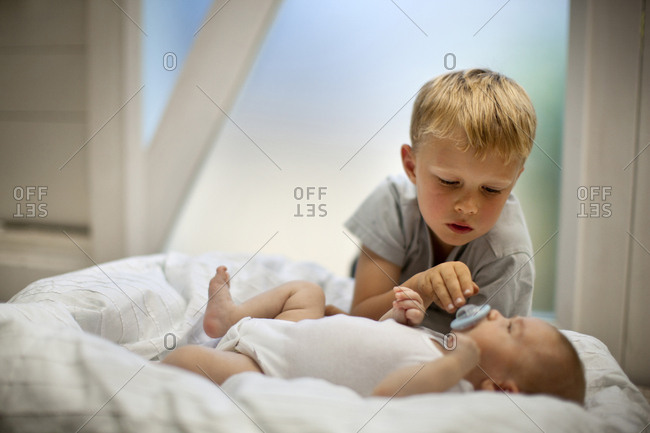 Young boy giving his baby sibling a pacifier