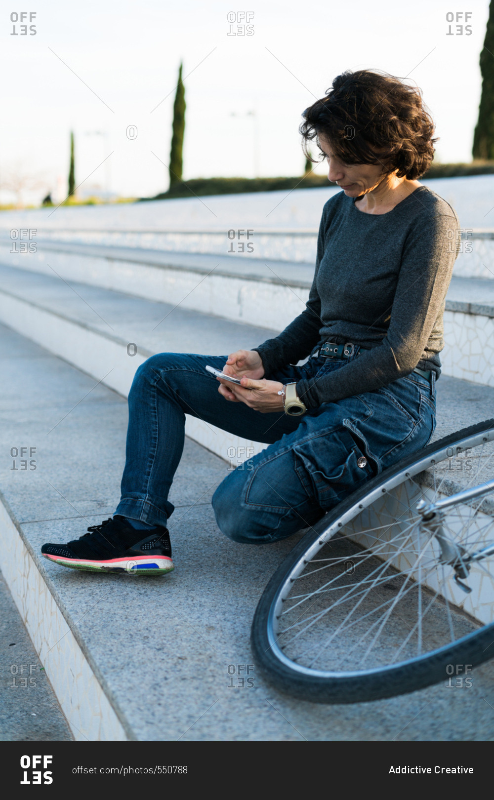 Woman sitting on stairs next to her bicycle
