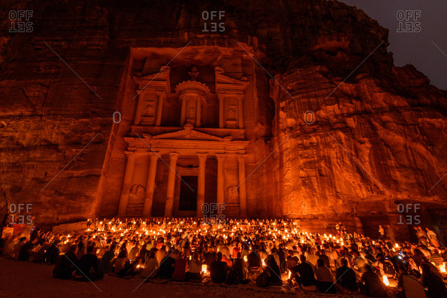 Many people sitting in front of the Al Khazneh temple in the ancient city of Petra in Jordan at night