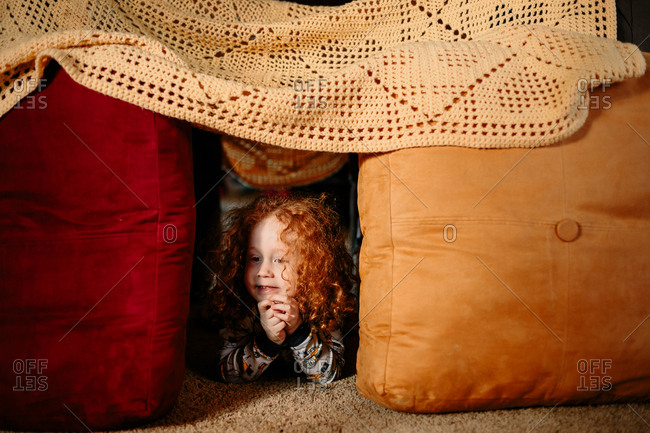 Child peeking out of pillow fort