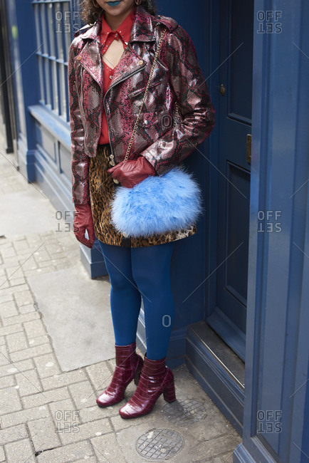 Woman in street with patent leather jacket and blue fur bag
