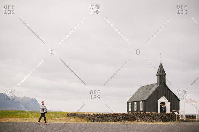 Snaefellsnes, Iceland - February 4, 2017: Man playing accordion walking toward church